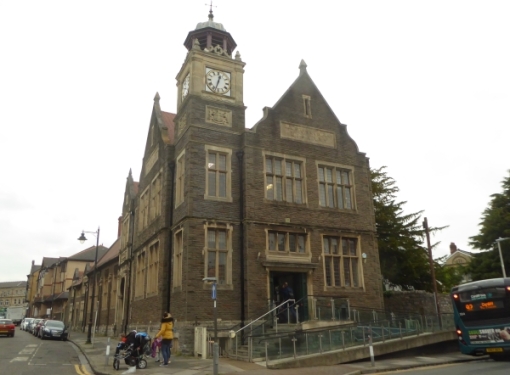 Two storey stone building on a corner plot, with clock tower